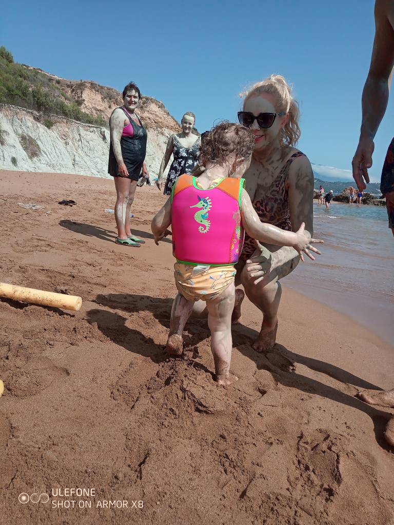 Woman and child on a sandy beach, covered in mud